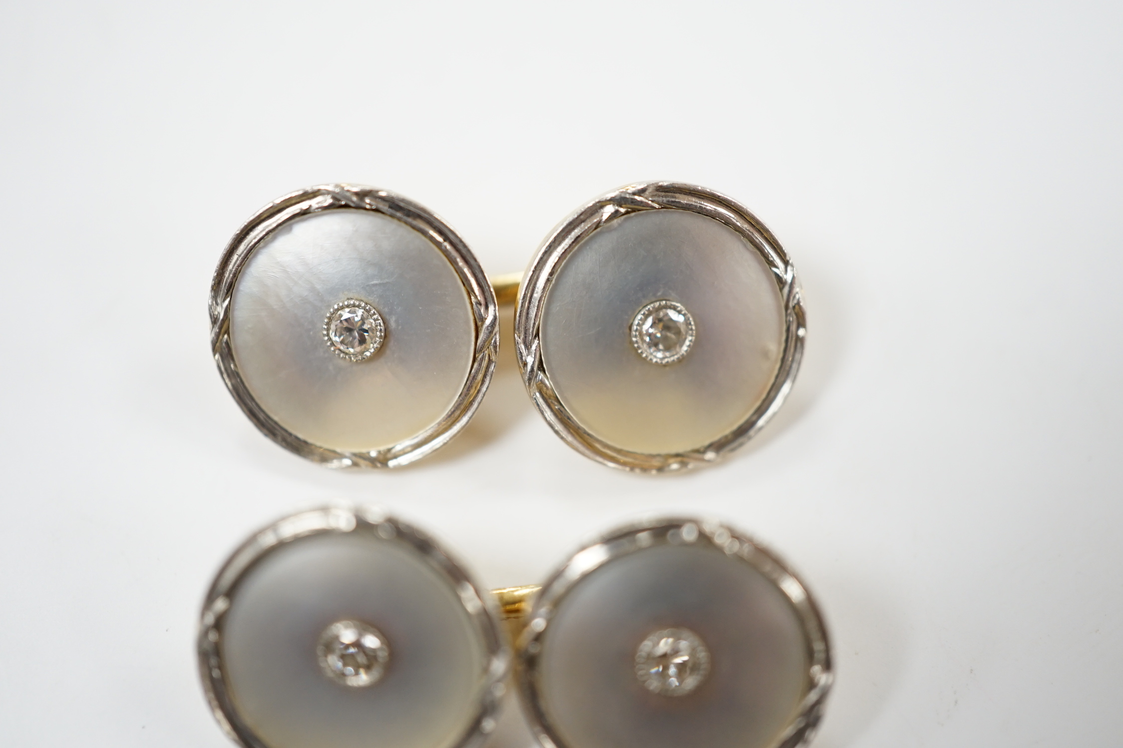 A pair of 14k yellow metal, mother of pearl and diamond chip set circular cufflinks, 12mm, gross weight 6.4 grams.